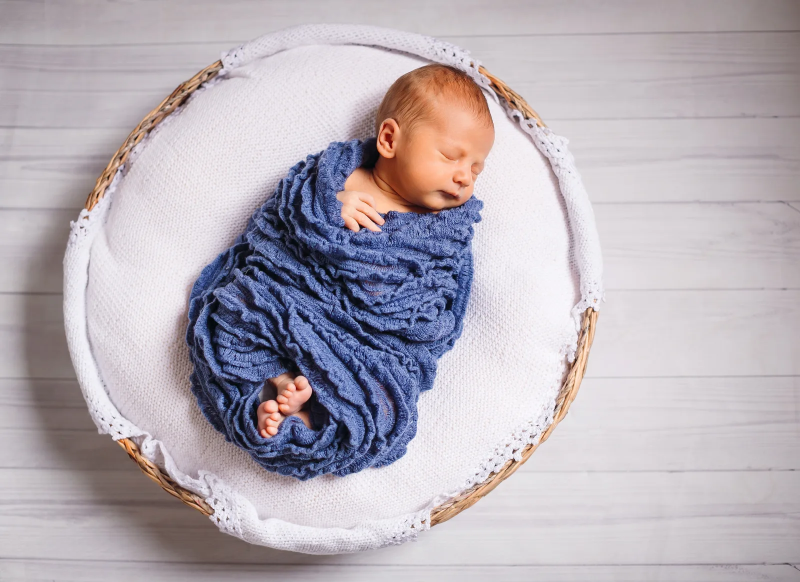 Newborn baby sleeping safely in a bassinet beside a caring parent